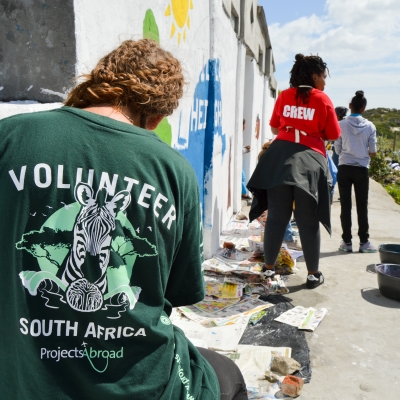 Team Trip volunteers in South Africa paint walls during a community work day Volunteers in South Africa assist with community maintenance work